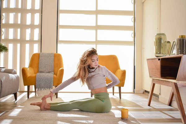 Una mujer practicando yoga en su sala.